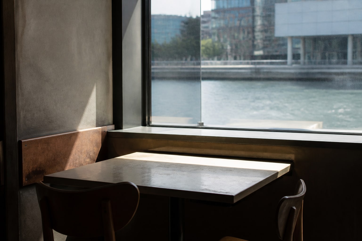 Hard summer light crossing an empty window table at Herzog Eats